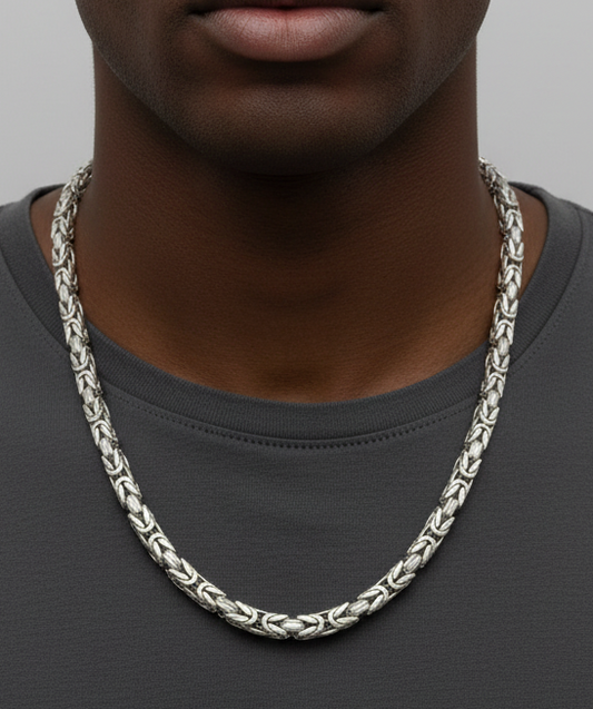 Man wearing a silver chain necklace against a plain background